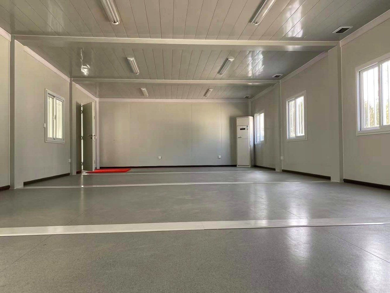 Large open interior room in big container house with white walls and fluorescent lighting