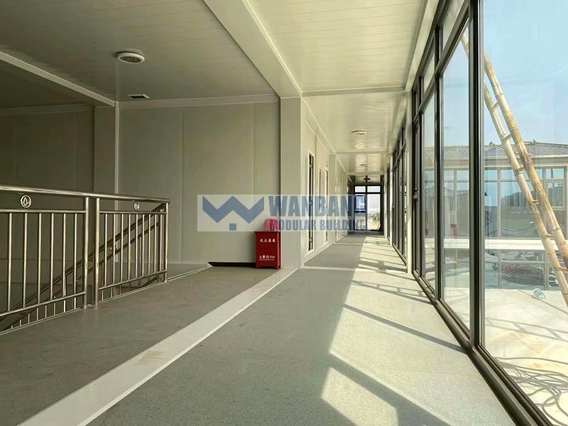 Glass corridor with aluminum railing and natural light in modular building