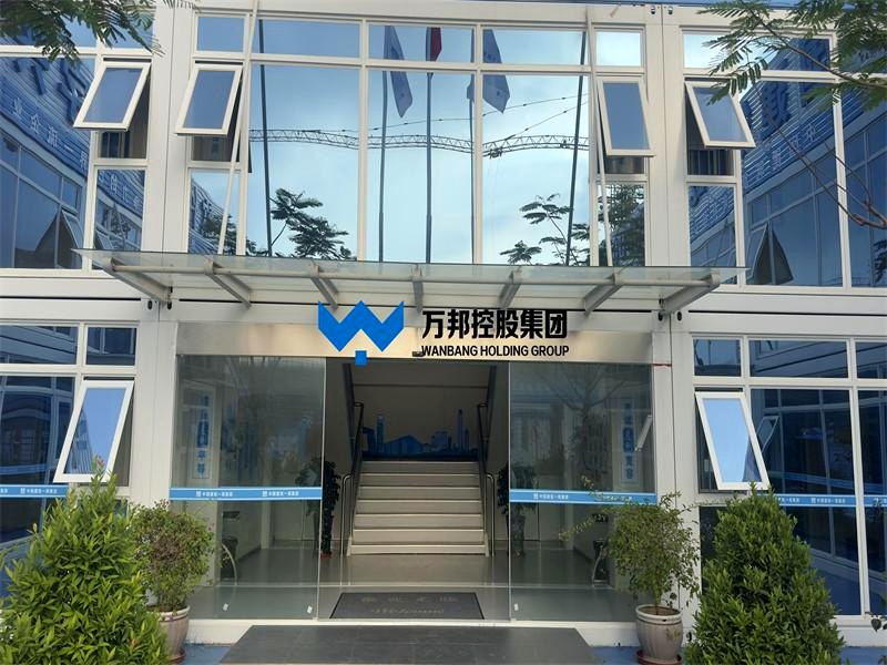 Two-story modular building entrance with glass doors and WANBANG branding