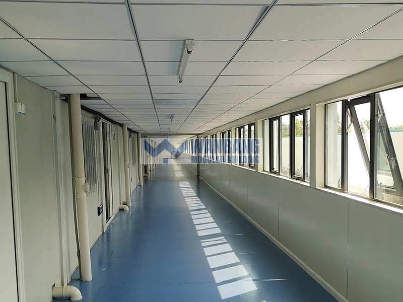 Interior corridor with blue floor and white walls in emergency shelter container house